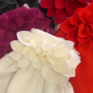 A collection of outfits, likely dresses or rompers for a young child, characterized by a very bold and voluminous large floral accent.