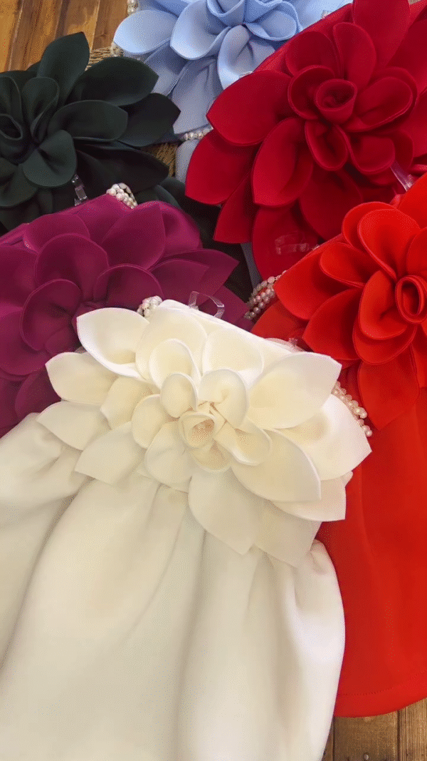 A collection of outfits, likely dresses or rompers for a young child, characterized by a very bold and voluminous large floral accent.