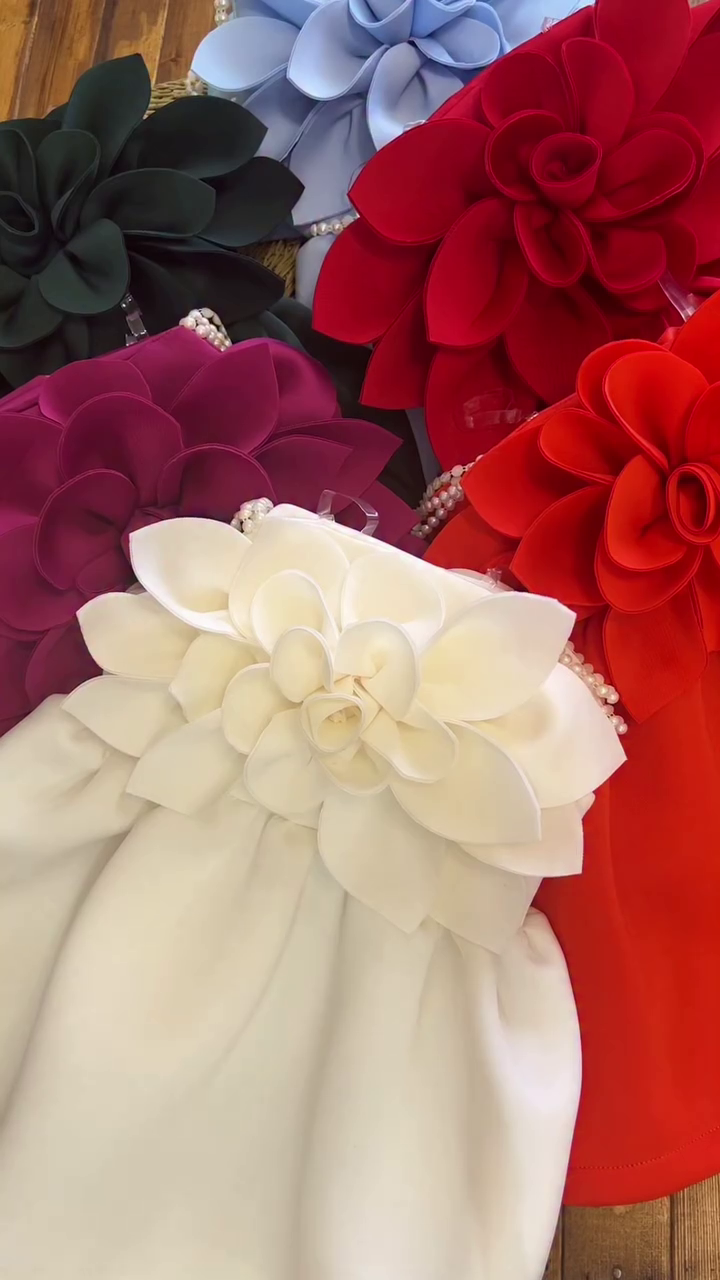 A collection of outfits, likely dresses or rompers for a young child, characterized by a very bold and voluminous large floral accent. - Image 4